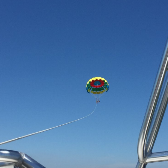 A rainbow parasail attached to the boat by a rope