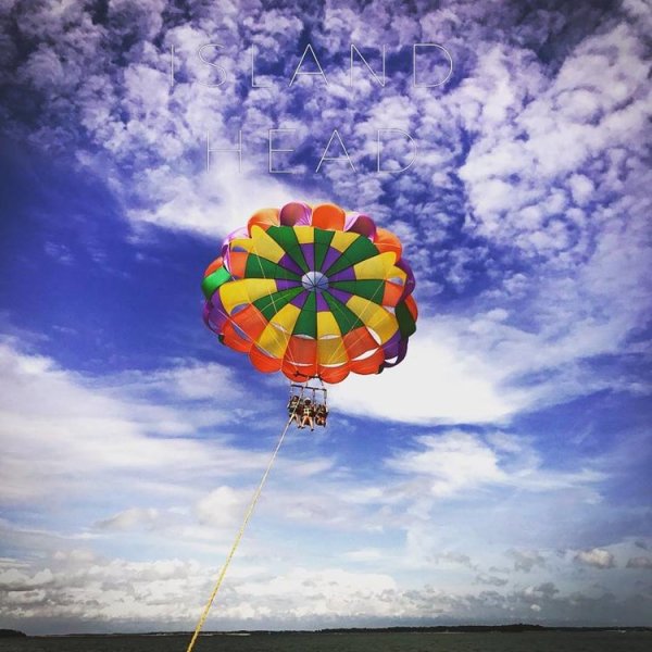 A rainbow parasail with three kids.